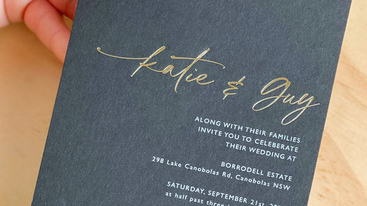 An image depicting a gold foil used in a wedding invitation. Printed on black card with.