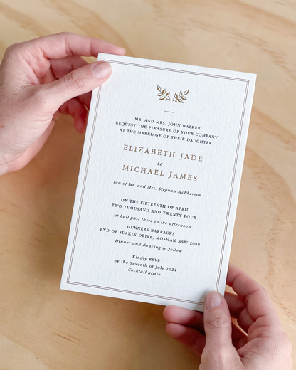 Our Elizabeth Wedding invitation card held by hands highlighting gold foil finish, by Communique Design.