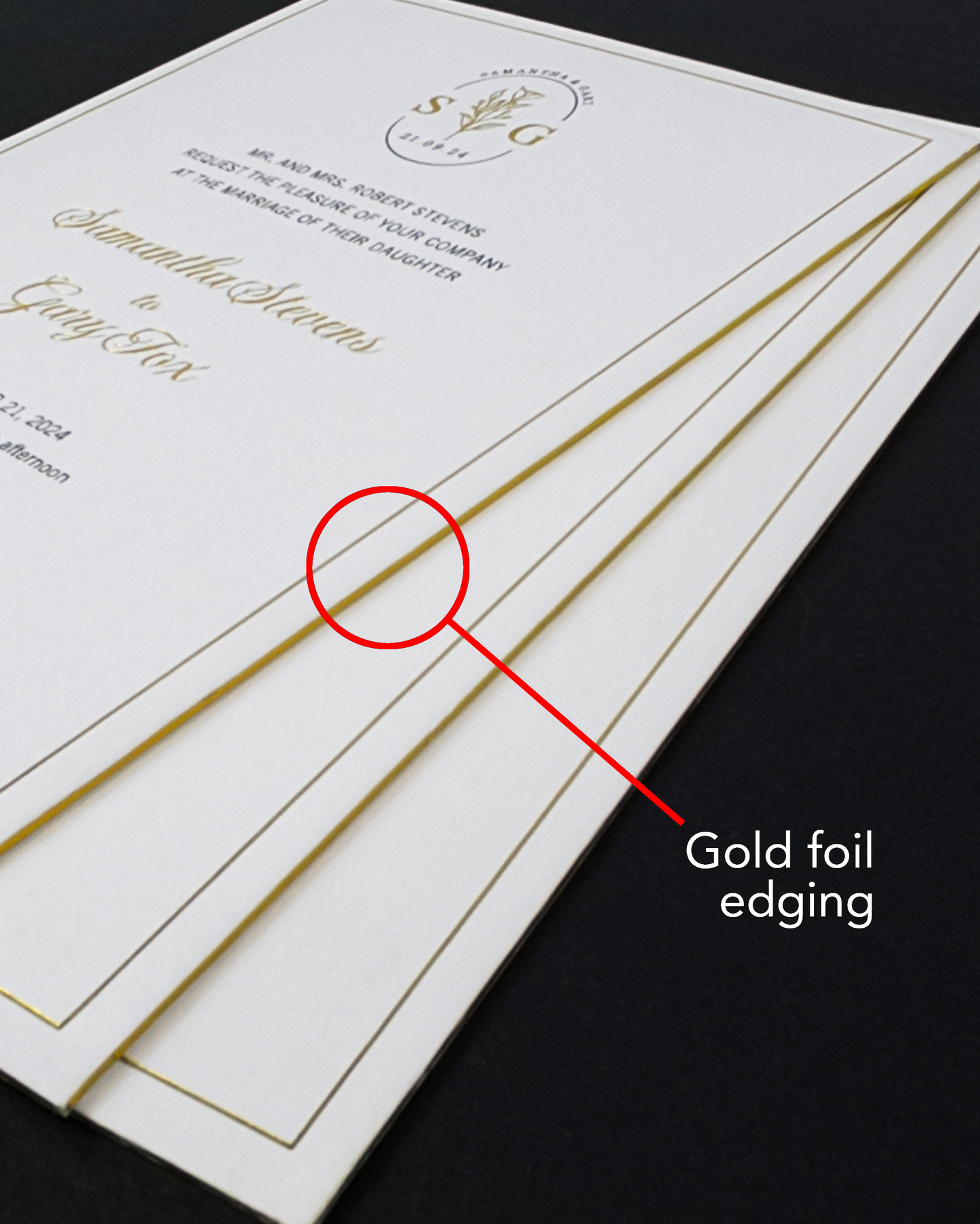 A stack of elegant Sorrento wedding invitations with gold foil edging, featuring gold script text and a circular monogram logo. A red circle and pointer label highlight the gold foil edge, with the text 'Gold foil edging' on a dark background.