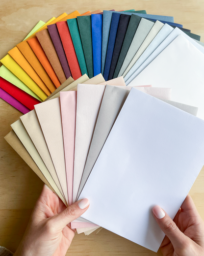 Color swatches of various colors held by hands on a wooden surface