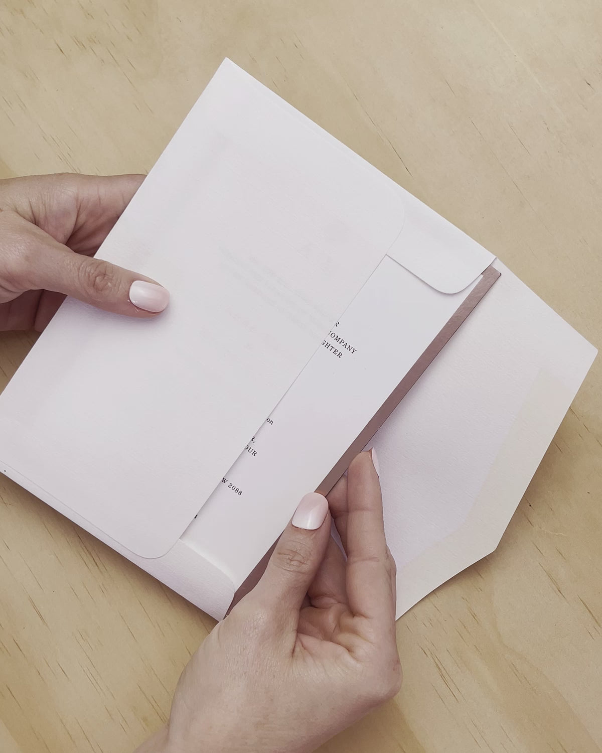 Duet wedding invitation shown being revealed from the envelop. Rose foil is a highlight of this invitation. A design by Communique Design.